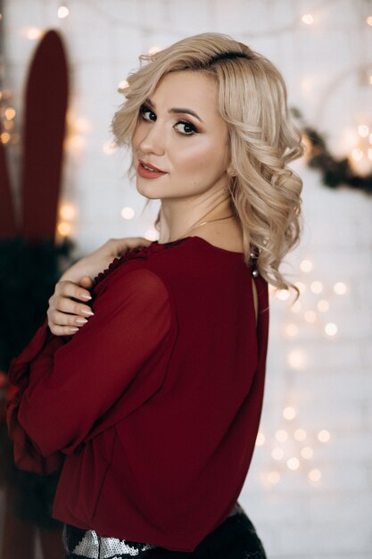 Fantaisie femme blonde vêtue de vêtements rouges se trouve dans une chambre avec un décor de Noël