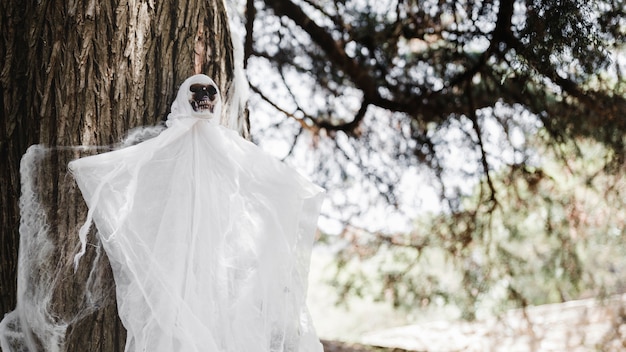 Photo gratuite fantôme sombre avec un visage de crâne suspendu à un arbre