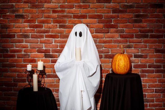 Fantôme tenant une bougie sur le mur de briques. Fête d'Halloween.