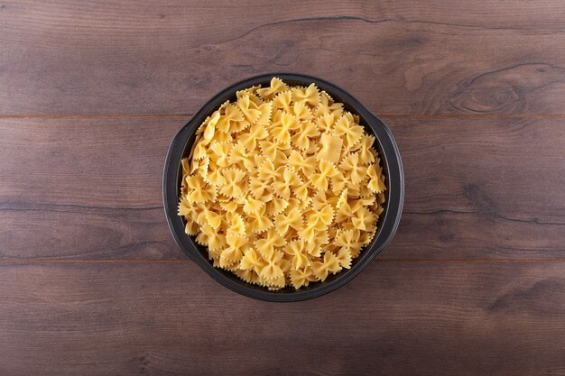 Farfalle pâtes dans un bol noir sur la surface en bois sombre vue de dessus