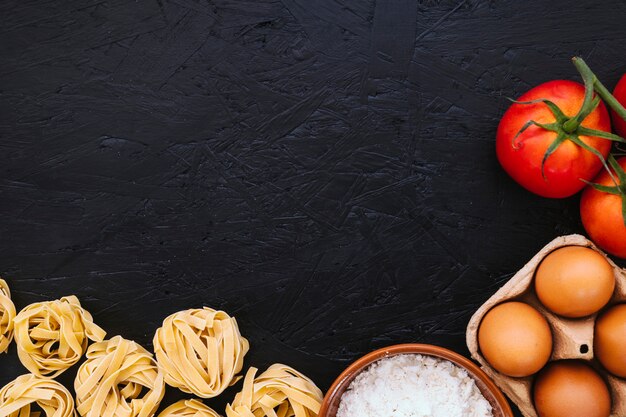 Farine et oeufs près de pâtes et tomates