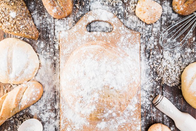 Farine sur la planche à découper et variété de pains sur la table