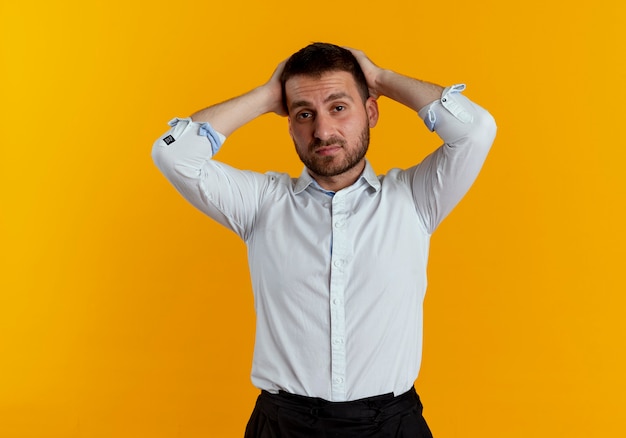 Fatigué bel homme tient la tête à deux mains isolé sur un mur orange