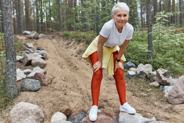 Fatigué épuisé femme d'âge moyen en vêtements de sport et chaussures de course se reposant après un entraînement cardio intense