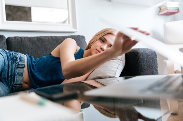 Fatigué femme allongée sur le canapé et fermer l'ordinateur portable à la maison