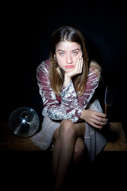 Fatigué femme assise avec un verre de champagne à la main