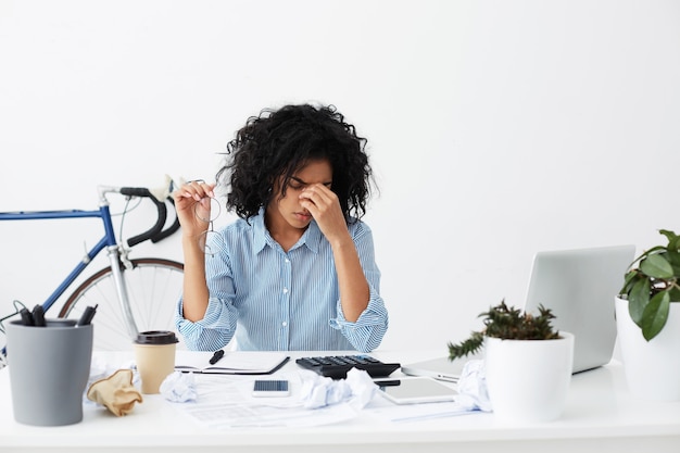 Photo gratuite fatigué de femme noire avec des lunettes à la main se frottant les yeux, plein de tristes pensées agitées