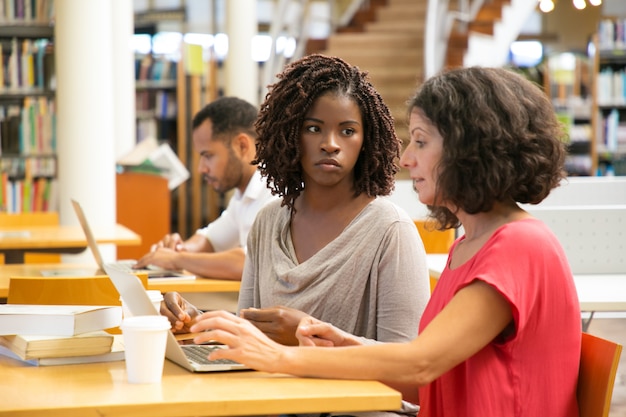 Fatigué femmes utilisant un ordinateur portable à la bibliothèque