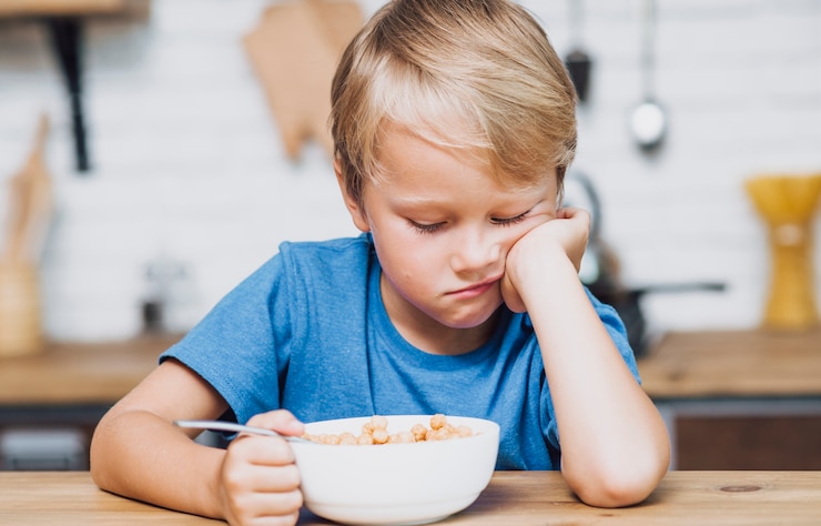 Photo gratuit fatigué garçon essayant de manger ses céréales