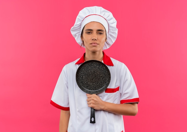 Fatigué de jeune femme cuisinier portant l'uniforme de chef tenant une poêle avec copie espace