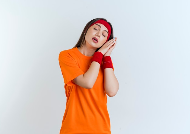 Fatigué de jeune femme sportive portant bandeau et bracelets faisant le geste de sommeil avec les yeux fermés isolés