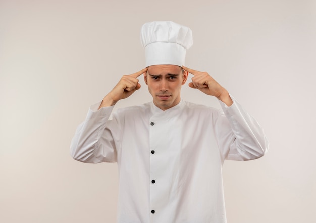 Photo gratuite fatigué de jeune homme cuisinier portant l'uniforme de chef mettant les doigts sur son front avec copie espace