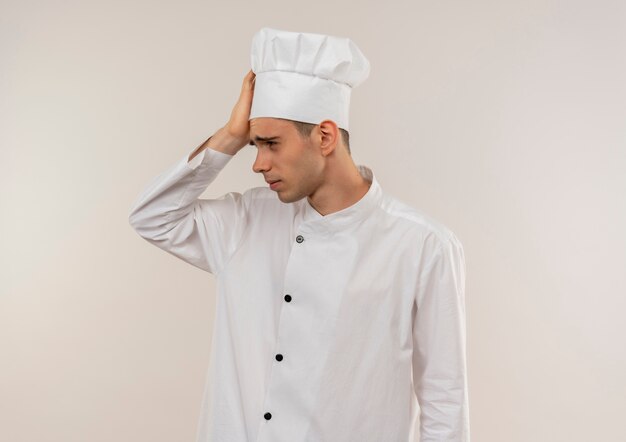 Fatigué de jeune homme cuisinier portant l'uniforme de chef mettant la main sur le front avec copie espace