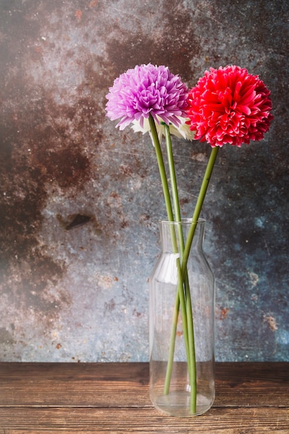 Fausses fleurs de chrysanthèmes dans le vase en verre sur fond grunge