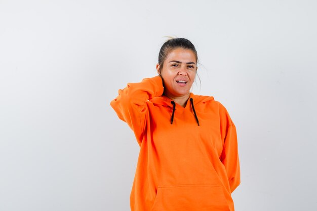 Femelle en orange hoodie tenant la main sur le cou et à la charmante