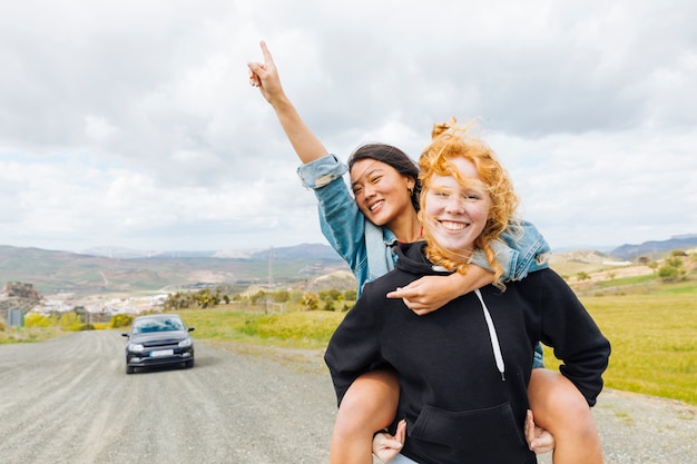 Photo gratuite femelles jouant sur le dos près d'une voiture garée