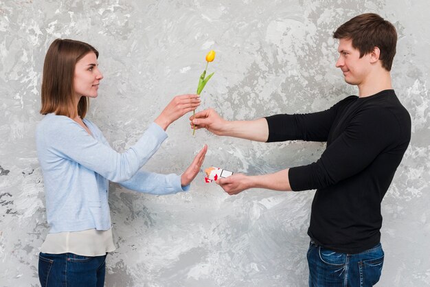 Femme acceptant une fleur de tulipe jaune et non aux paquets de cigarettes offerts par un bel homme