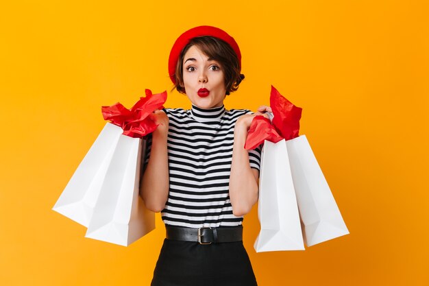 Femme accro du shopping attrayant debout sur un mur jaune