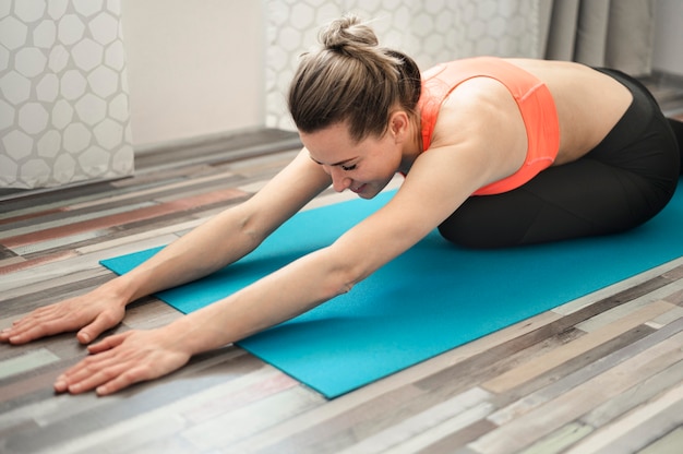 Femme active qui s'étend sur un tapis de yoga