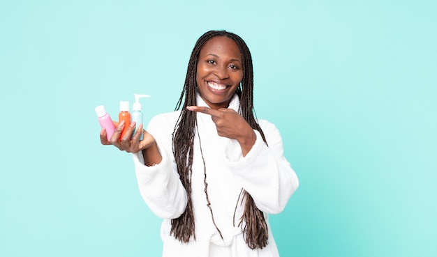 Femme adulte afro-américaine noire portant un peignoir et tenant des produits cosmétiques