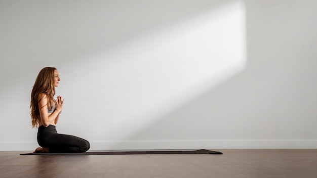 Femme adulte, faire du yoga à la maison