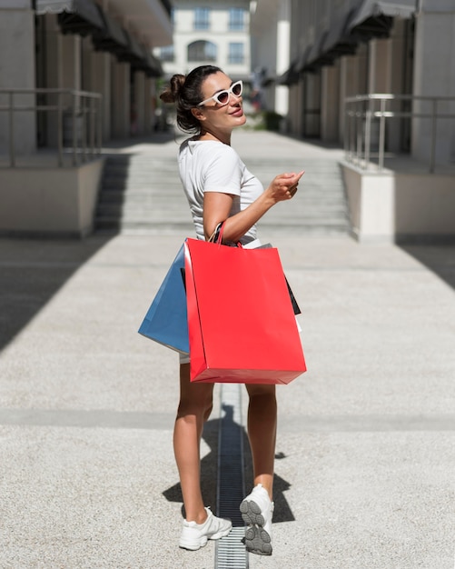 Photo gratuite femme adulte posant avec des sacs à provisions