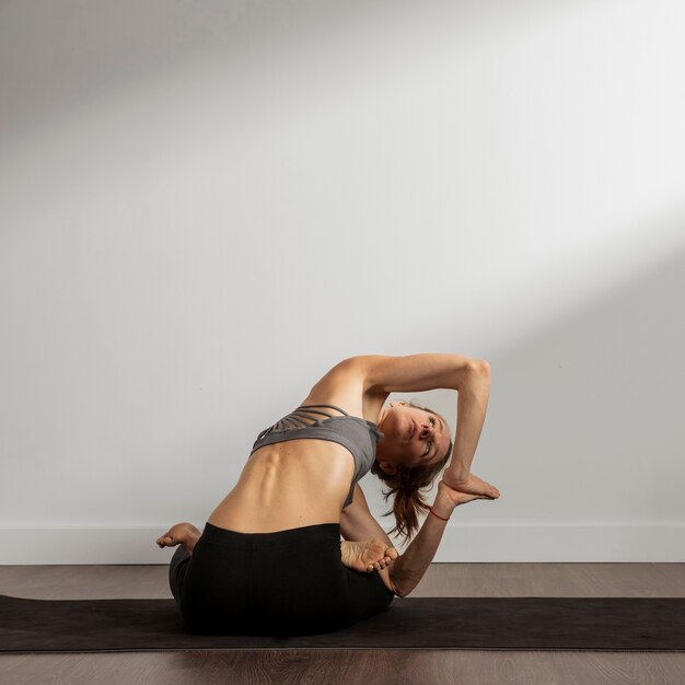 Femme adulte pratiquant le yoga à la maison