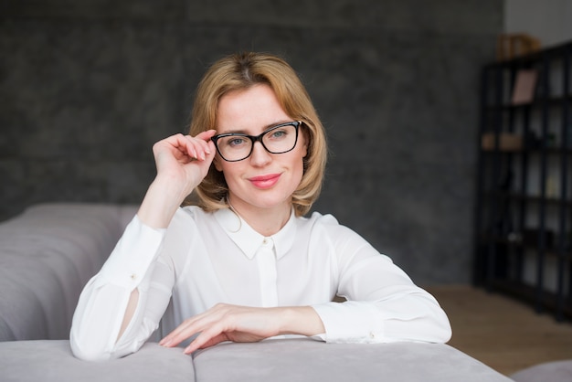 Femme d&#39;affaire blonde à lunettes assis sur un canapé