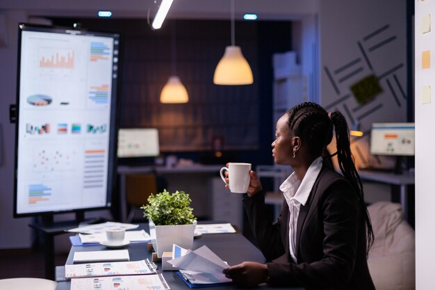 Femme d'affaires afro-américaine bourreau de travail analysant les statistiques de marketing sur la paperasse