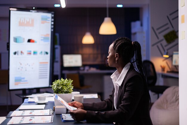 Une femme d'affaires afro-américaine, bourreau de travail, travaillant à la présentation des graphiques financiers de l'entreprise