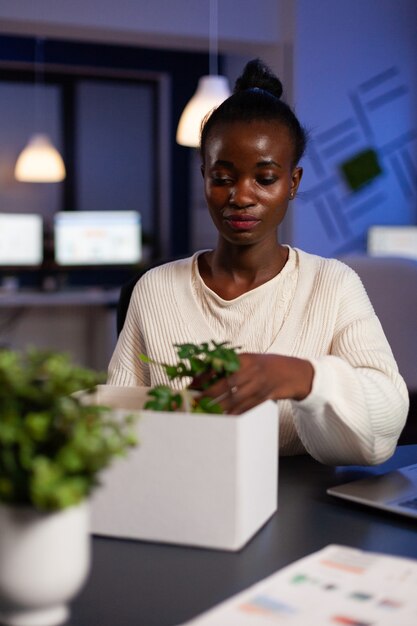 Femme d'affaires afro-américaine déplacée mettant des objets dans une boîte en carton