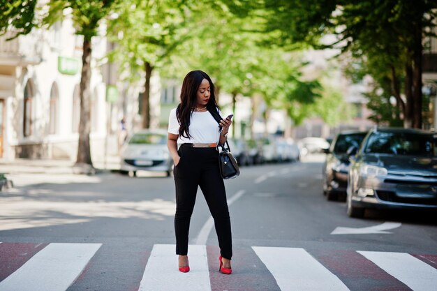 Femme d'affaires afro-américaine élégante dans les rues de la ville au passage pour piétonsxA