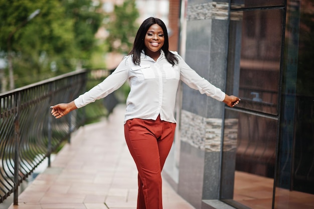 Femme d'affaires afro-américaine formellement habillée en chemisier blanc et pantalon rouge