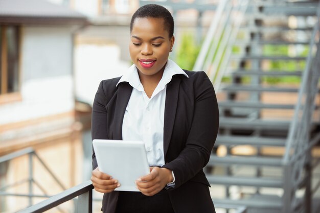 Femme d'affaires afro-américaine en tenue de bureau à l'aide d'une tablette