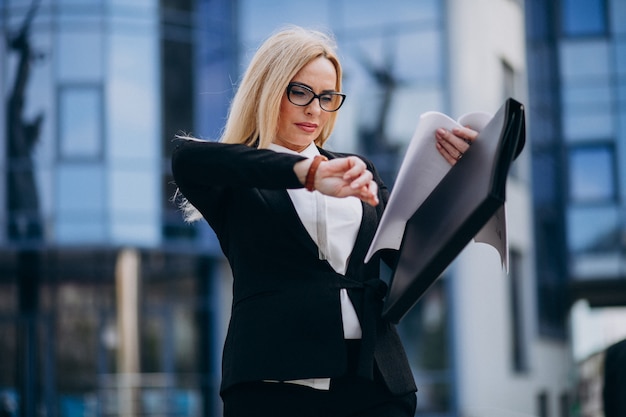 Femme d'affaires d'âge moyen tenant des documents par le centre d'affaires