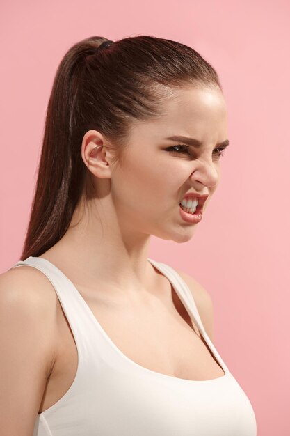 Femme d'affaires agressive debout isolée sur un mur de studio rose à la mode
