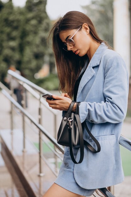 Femme d'affaires à l'aide de téléphone à l'extérieur de la rue