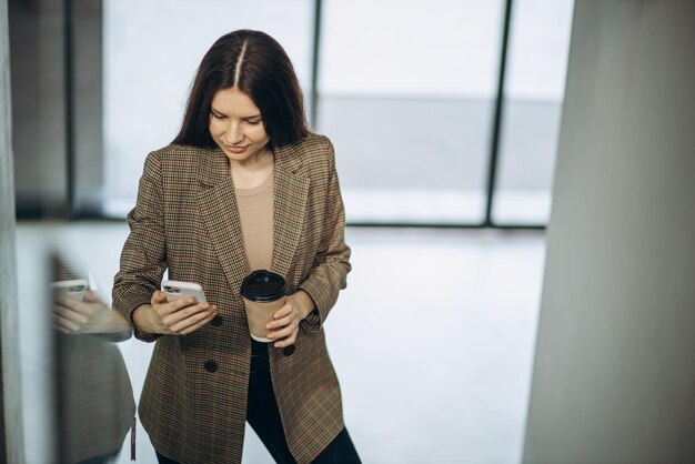 Femme d'affaires à l'aide de téléphone portable à l'immeuble de bureaux