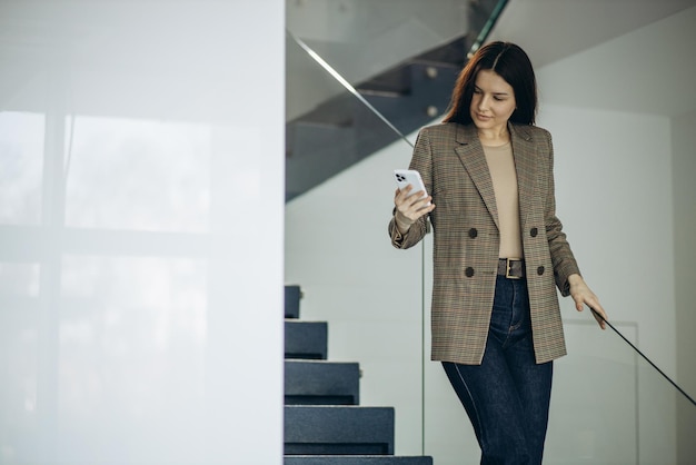 Femme d'affaires à l'aide de téléphone portable à l'immeuble de bureaux