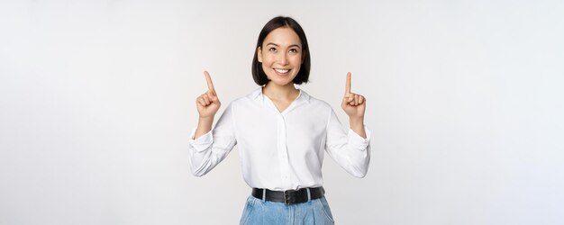 Femme d'affaires asiatique enthousiaste pointant vers le haut avec un visage souriant heureux montrant le logo de l'entreprise o