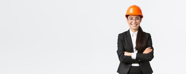 Femme d'affaires asiatique souriante professionnelle portant un casque de sécurité et une combinaison de bras croisés et ayant l'air confiant de vendre de nouveaux bâtiments Ingénieur en chef de la construction montrant autour de saluer les investisseurs