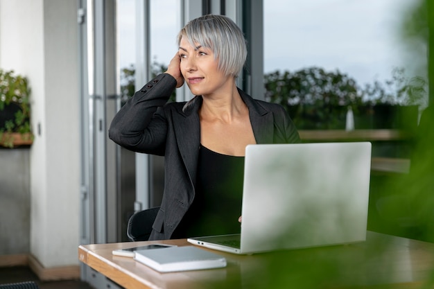 Photo gratuite femme d'affaires assis et regardant au loin