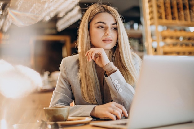 Femme d'affaires assise dans un café et travaillant en ligne