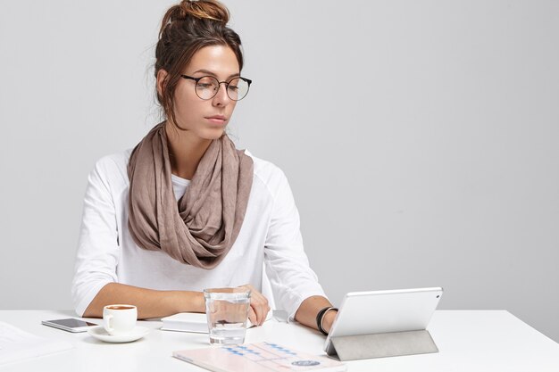 Femme d'affaires au bureau travaille sur tablette numérique, regardez sérieusement.