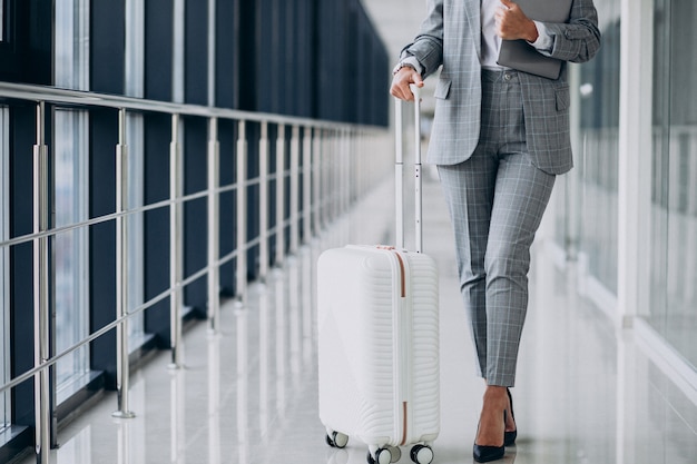 Femme d'affaires avec des bagages de voyage à l'aéroport, tenant un ordinateur portable