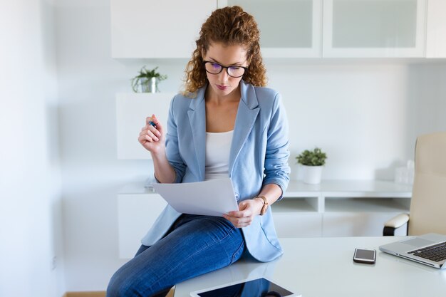 Femme d&#39;affaires belle relecture des documents dans le bureau.