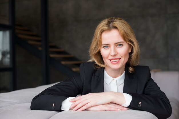 Femme d&#39;affaires blonde assise sur un canapé et souriant