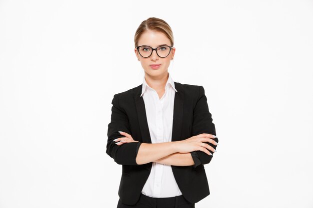 Femme d'affaires blonde cool à lunettes posant avec les bras croisés sur blanc