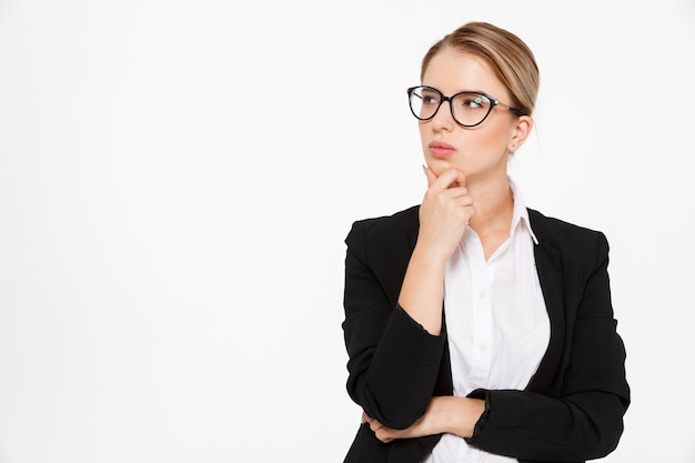 Femme d'affaires blonde pensive sérieuse à lunettes à l'écart sur blanc