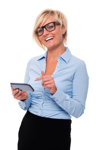 Femme d'affaires blonde souriant et pointant sur téléphone mobile